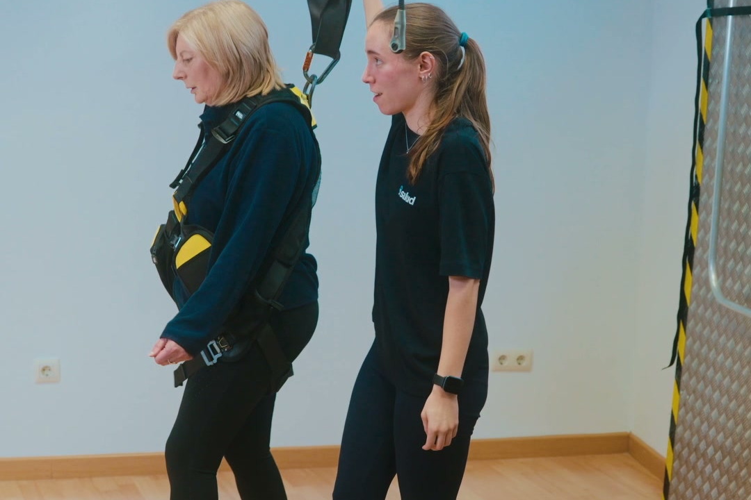Fisioterapeuta acompañando a una paciente con arnés de valoración durante la marcha